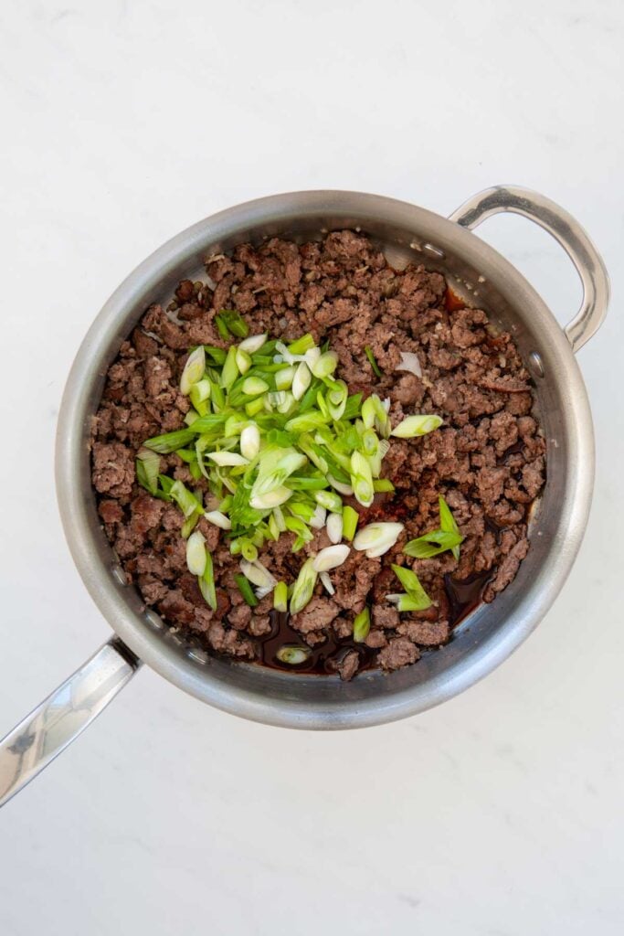 chopped green onions added to skillet with cooked ground beef and brown sugar soy sauce mixture