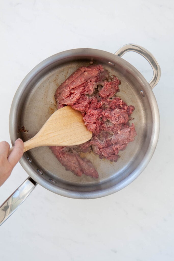 breaking apart ground beef in a skillet