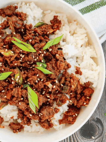 Craving a fast dinner that's packed with flavor? These Korean Ground Beef Bowls are the ultimate weeknight meal, made with tender ground beef coated in a sweet, savory, and slightly spicy Korean-inspired sauce with soy sauce, brown sugar, garlic, ginger, sesame oil, and gochujang. Served over fluffy rice and topped with green onions and sesame seeds, this easy Ground Beef Bowl is ready in just 15 minutes. Perfect for Easy Ground Beef Recipes, Korean Beef Rice Bowls, Ground Beef Dinner Ideas, Quick Family Meals, Asian Inspired Recipes, Weeknight Dinner Recipes, Meal Prep Bowls, Rice Bowl Recipes, Ground Beef and Rice, and Budget Friendly Dinners, this simple recipe is one you'll make again and again.