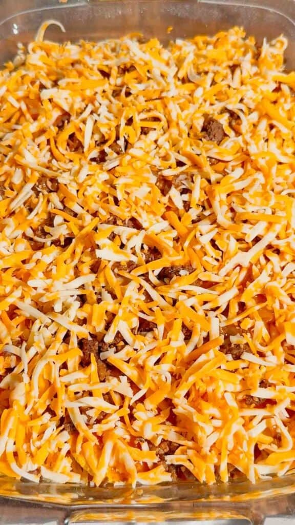 shredded cheddar cheese on top of lazy enchiladas in a baking dish