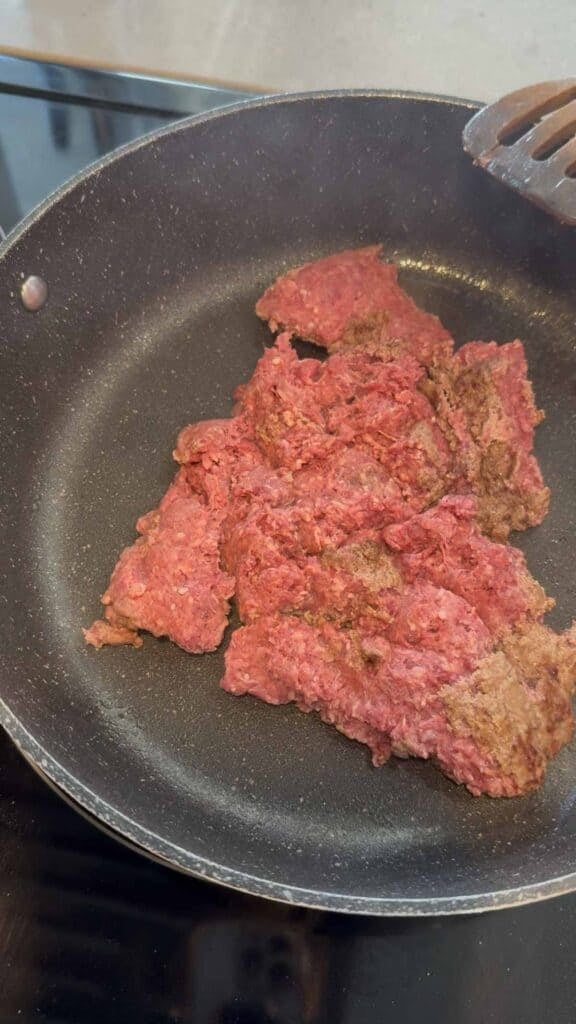raw ground beef cooking in a skillet