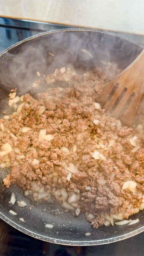 cooked ground beef and diced onions in a skillet