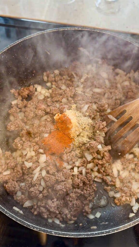 seasoning added to skillet with cooked ground beef