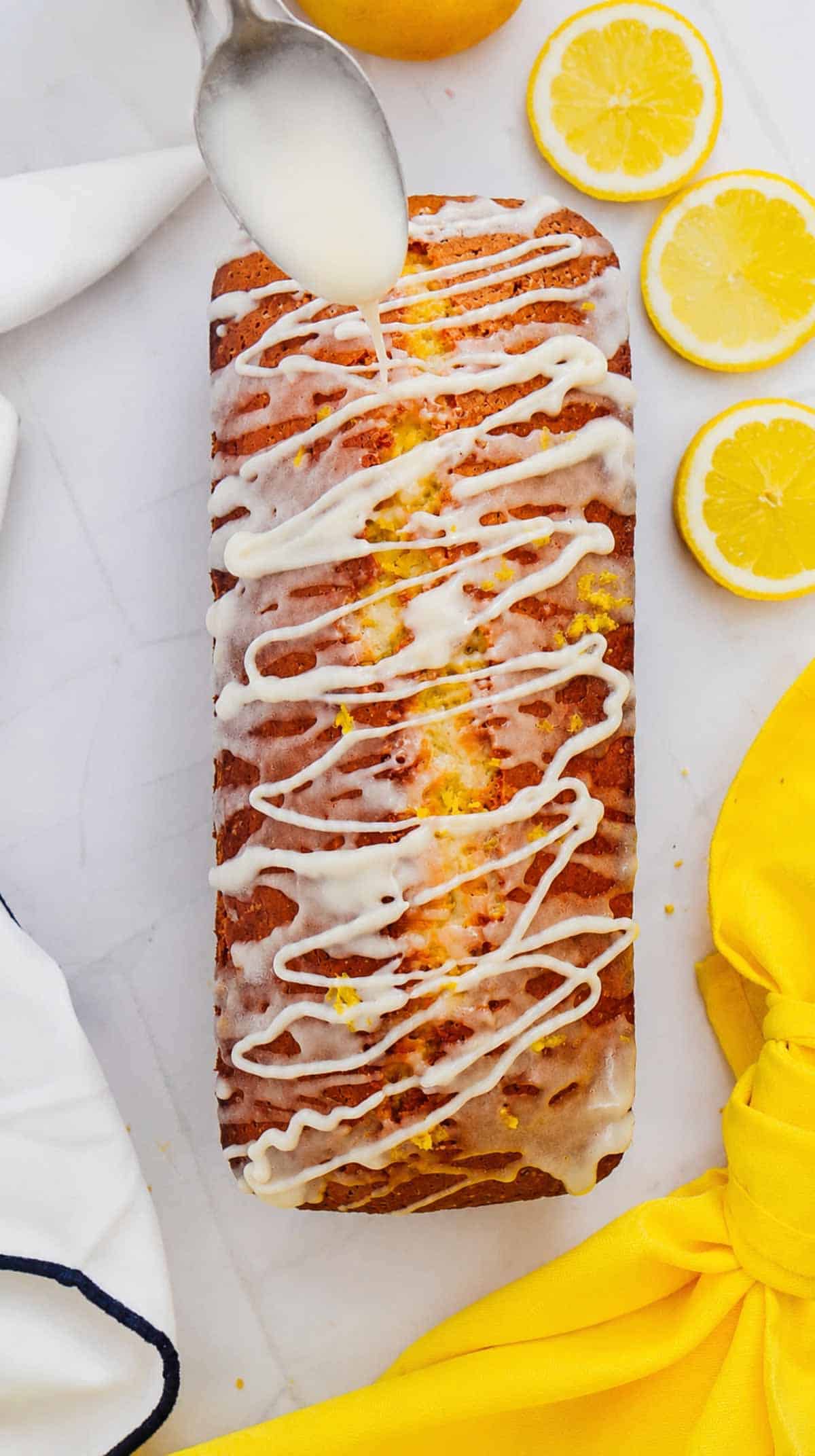 cream cheese frosting being drizzled over lemon loaf