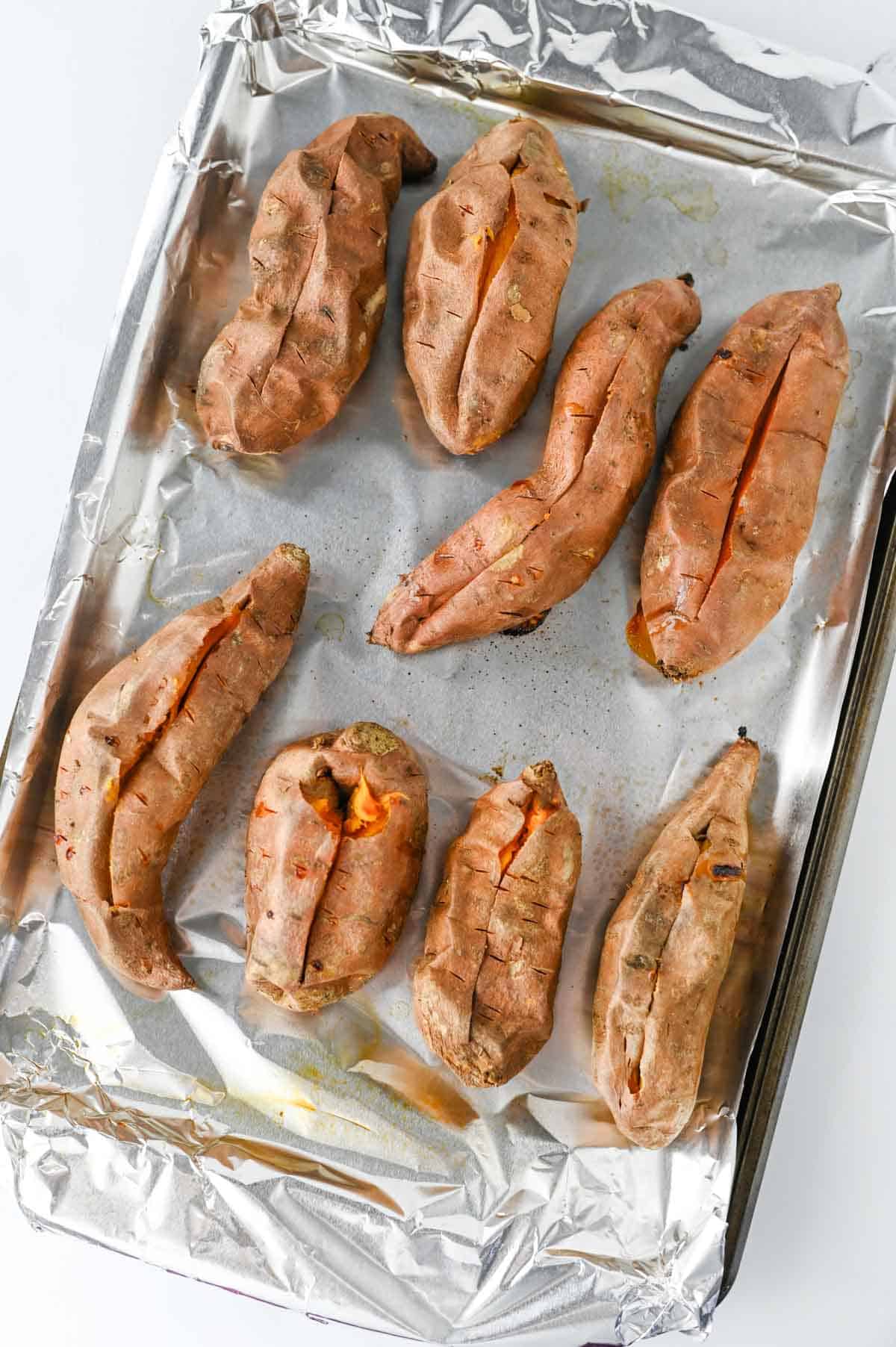 baked sweet potatoes on a foil lined baking sheet