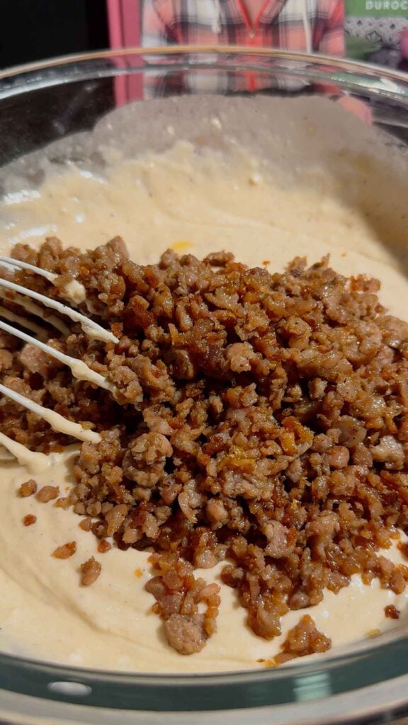 cooked and crumbled sausage added to bowl with pancake batter