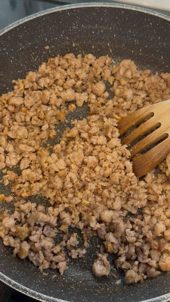 cooking and crumbling sausage in a skillet