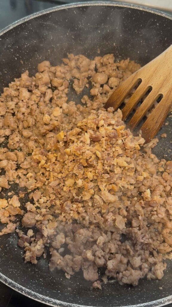 crumbled bacon added to skillet with cooked sausage