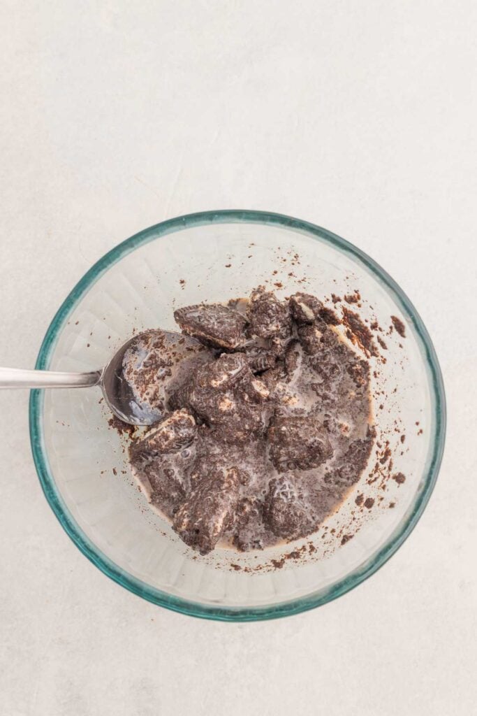 stirring crushed oreos and milk together in a glass mug