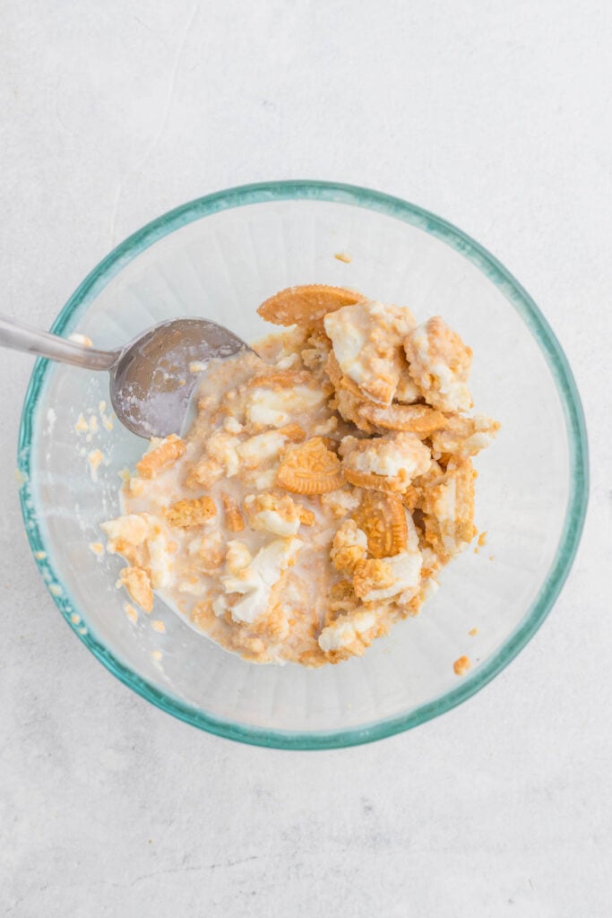 stirring crushed golden oreos and milk together in glass mug