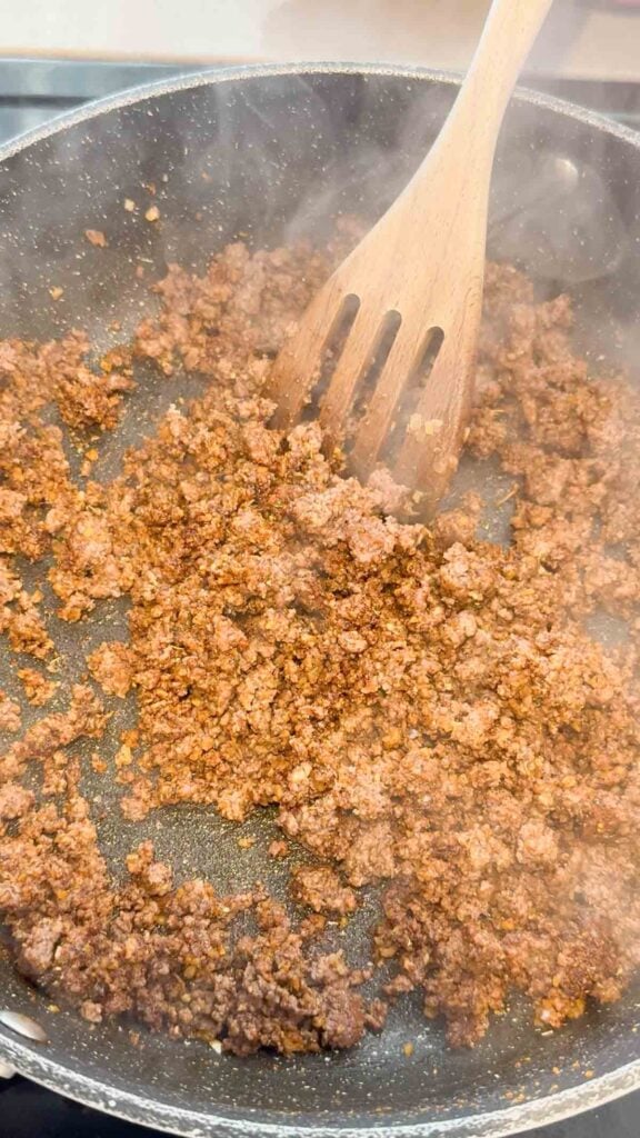 stirring taco seasoning onto ground beef in a skillet