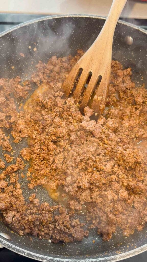 stirring seasoned taco beef in a skillet