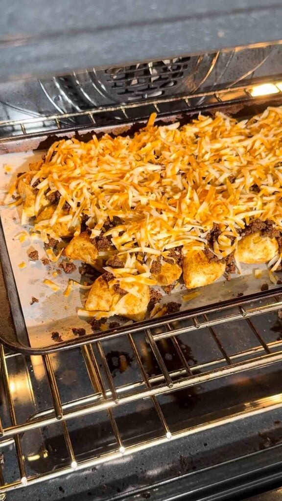 shredded cheese on top of pierogi nachos in the oven