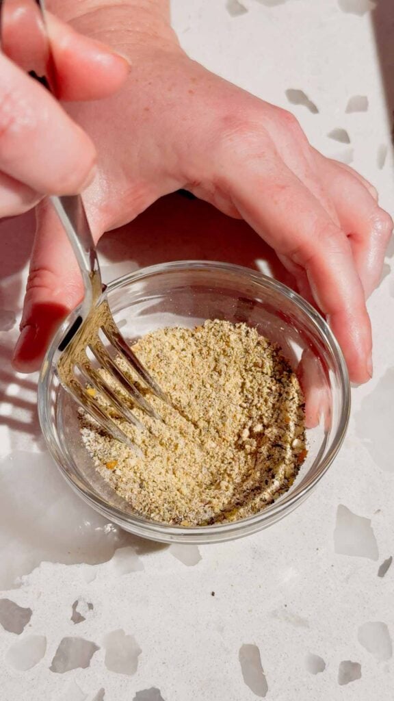 stirring seasoning together with a fork in a small glass bowl