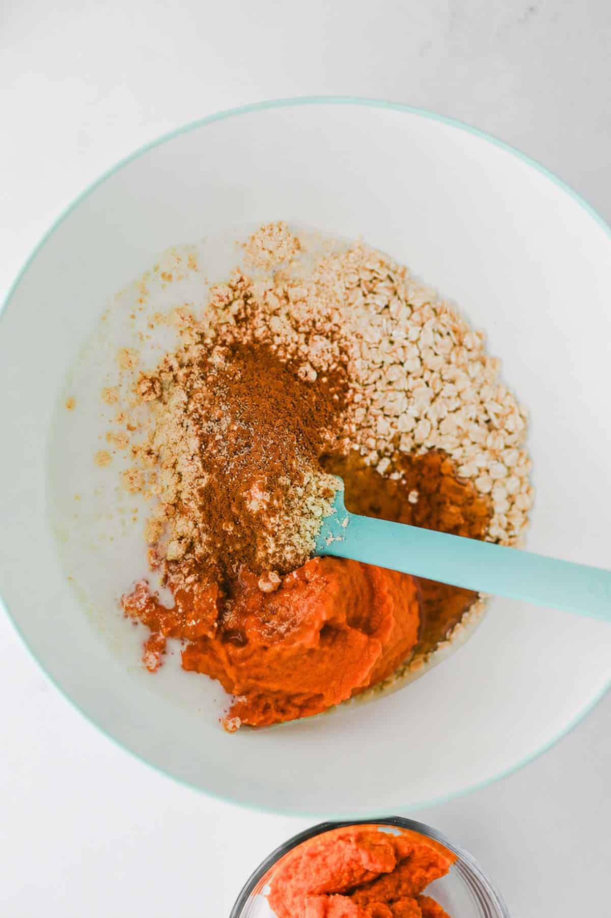 oats, protein powder, pumpkin pie spice, pumpkin puree, milk, and maple syrup all in a mixing bowl