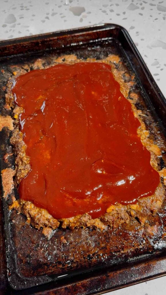 bbq sauce spread on top of sheet pan meatloaf