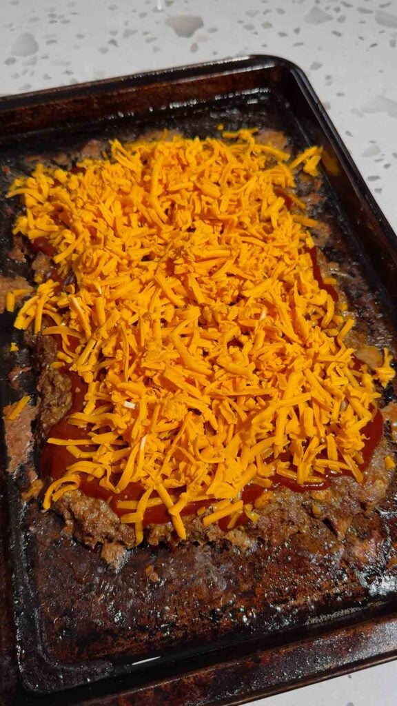shredded cheddar and bbq sauce on top of sheet pan meatloaf