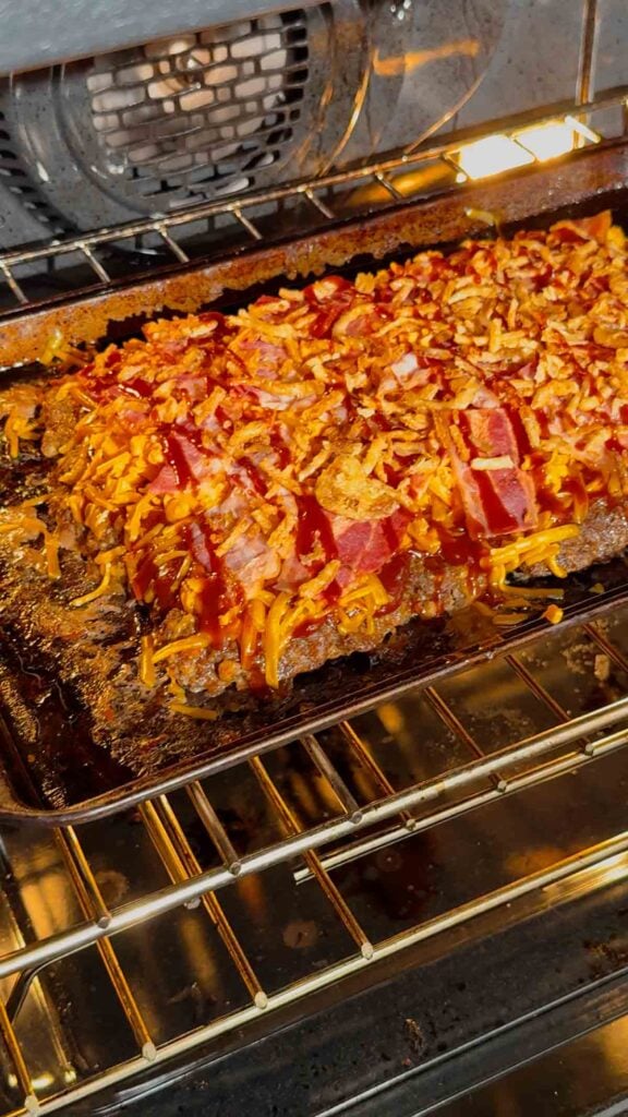 bbq bacon cheeseburger mealoaf on a sheet pan baking in the oven
