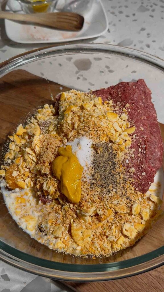 salt, pepper, mustard, ritz cracker crumbs and raw ground beef in a glass bowl