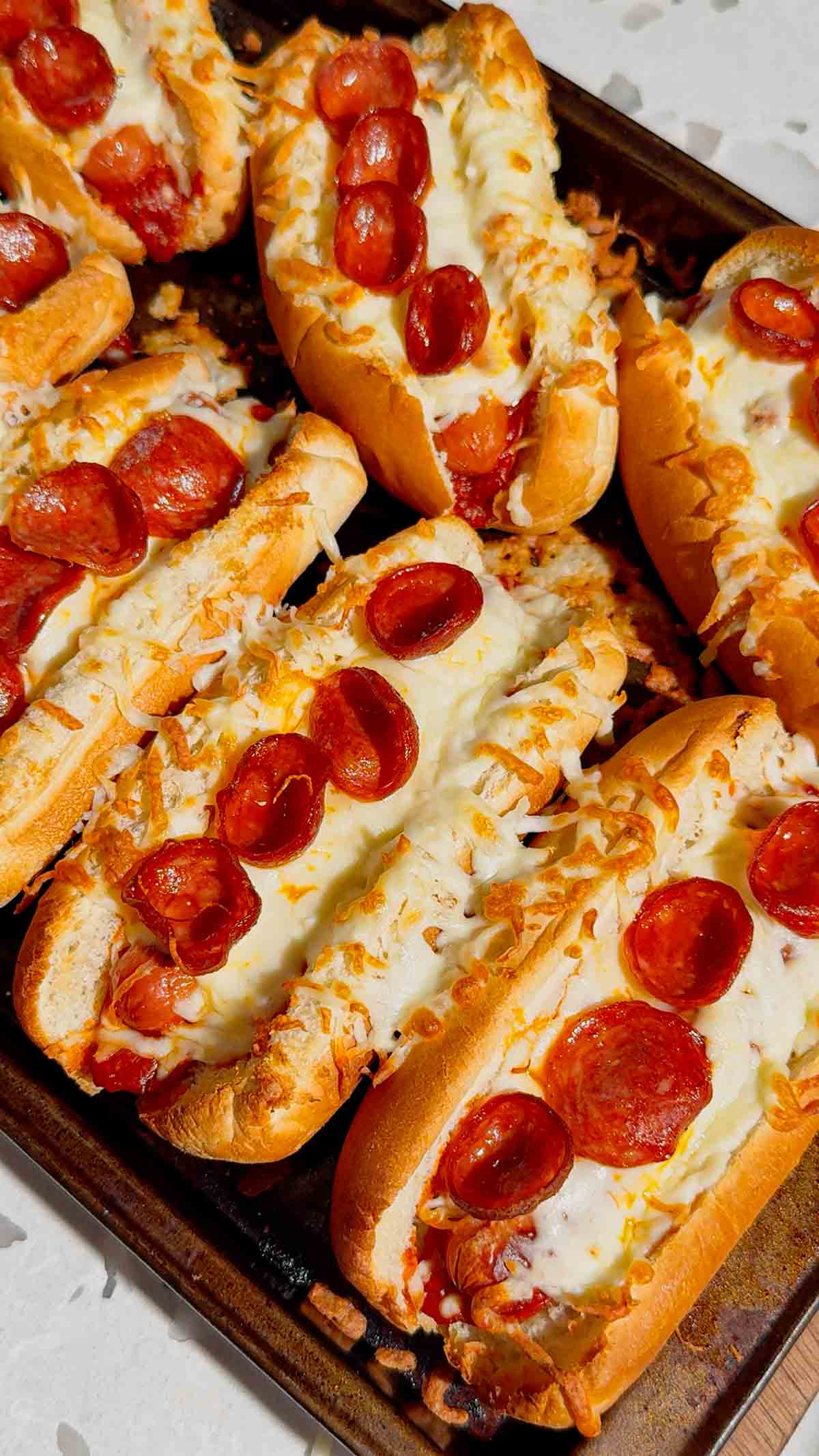 These Sheet Pan Pizza Dogs are the ultimate easy family dinner for busy nights! If you're looking for Weeknight Dinner Ideas, Easy Dinner Recipes For Family, or Quick Dinner Ideas everyone will actually eat, this fun mashup of pizza and hot dogs is a guaranteed winner. Crispy hot dog buns are loaded with pizza sauce, pepperoni, melty mozzarella cheese, and juicy hot dogs for a cheesy meal that's ready in under 20 minutes. Perfect for Lazy Dinners, Kid Friendly Meals, Game Day Food, Easy Supper Recipes, Family Dinner Ideas, Quick And Easy Dinner Recipes, Budget Friendly Meals, Easy Sheet Pan Recipes, Pizza Recipes, Hot Dog Recipes, and Simple Weeknight Meals. Save this easy pizza dog recipe for your next fast dinner, party, or fun family meal!