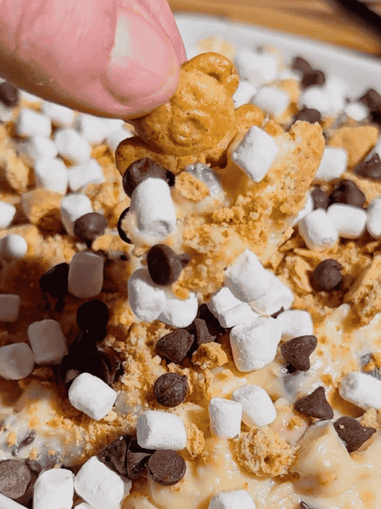 Looking for the ultimate S'mores Cookie Dough Dip to impress a crowd? This easy no bake dessert dip is rich, creamy, and loaded with mini chocolate chips, graham cracker crumbs, and marshmallows for that classic campfire flavor everyone loves. Perfect for Dessert Dips, No Bake Desserts, Easy Party Desserts, Cookie Dough Dip, S'mores Dessert Recipes, Summer Dessert Ideas, Sweet Dip Recipes, Holiday Dessert Ideas, Potluck Desserts, Game Day Desserts, Easy Dessert Recipes, and Fun Family Treats. Serve it with graham crackers, vanilla wafers, pretzels, strawberries, or apple slices for an irresistible dessert platter that's ready in only 10 minutes. Save this quick and easy dessert recipe for your next party, BBQ, movie night, or family gathering!