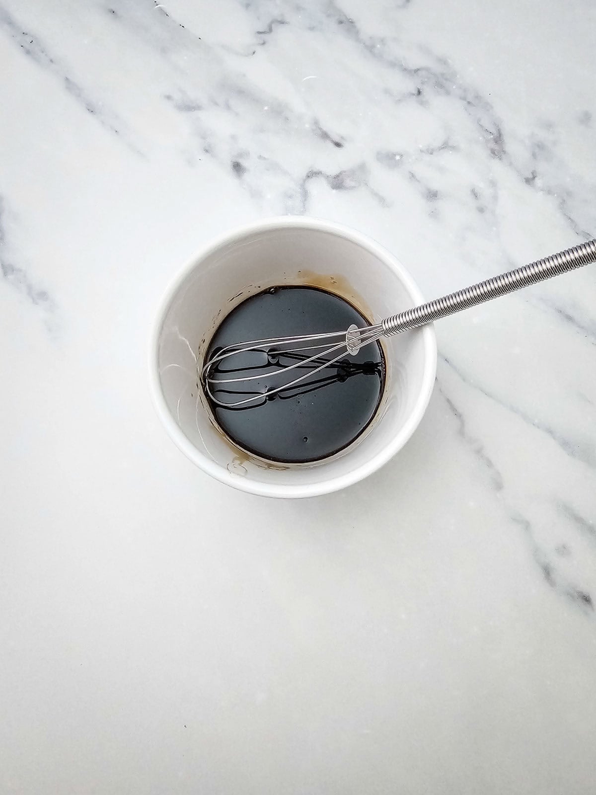 balsamic dressing being whisked in bowl