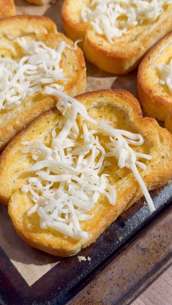 shredded mozzarella cheese on toasted garlic toasts