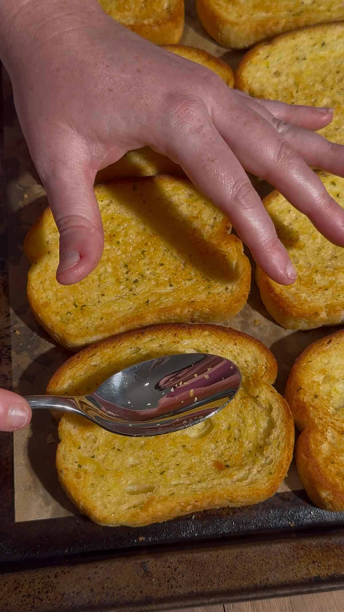 press a spoon down into a toasted slice of garlic bread