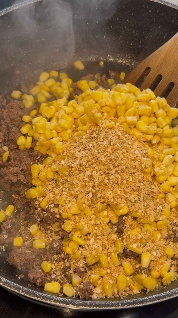 dehydrated minced onion and frozen corn added to skillet with cooked ground beef