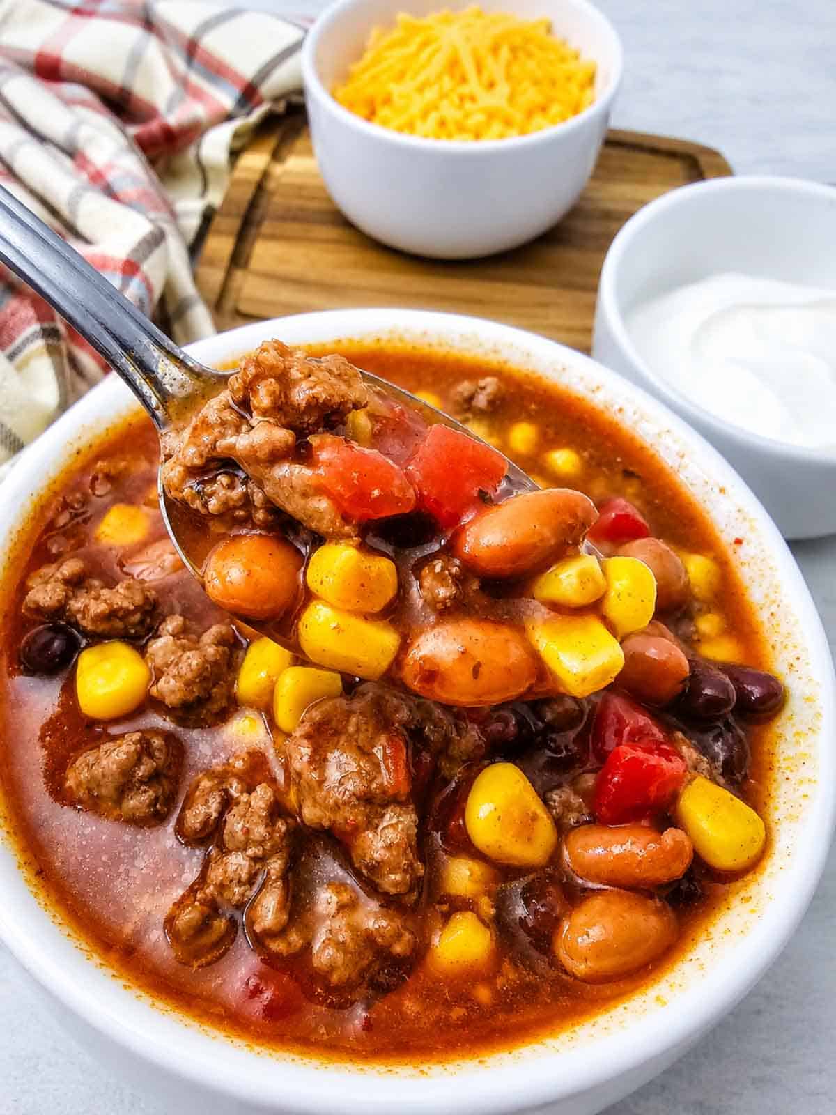 This easy 7 Can Taco Soup is the ultimate cozy dinner when you want big flavor with minimal prep! Loaded with seasoned ground beef, black beans, pinto beans, corn, diced tomatoes, green chilis and enchilada sauce, this hearty Taco Soup Recipe comes together with simple pantry staples in one pot. Taco seasoning, ranch seasoning, garlic, smoked paprika and cumin give every spoonful bold Tex-Mex flavor. Add this easy soup to your list of One Pot Dinner Ideas, Ground Beef Soup Recipes, Easy Taco Soup Recipes and Comfort Food Recipes. It’s perfect for busy weeknights, chilly fall dinners, meal prep or feeding the whole family. If you love Mexican Inspired Recipes, hearty Beef Soup Recipes and easy canned food recipes, save this 7 Can Taco Soup Recipe for a warm and satisfying dinner everyone will love!