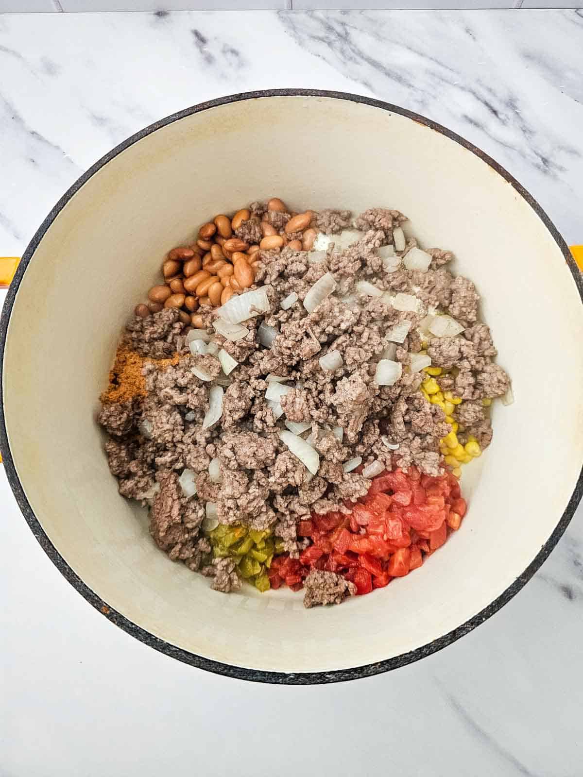 cooked ground beef and diced onions added to pot with beans and corn