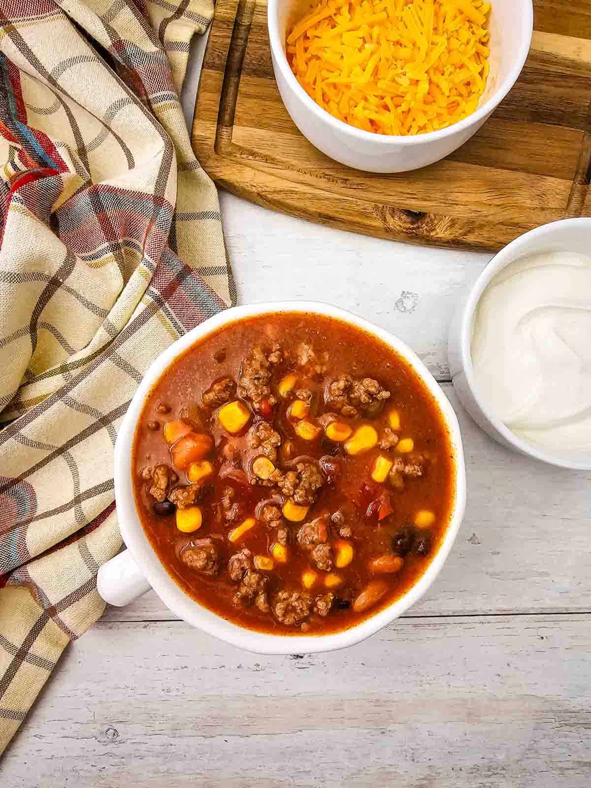 This easy 7 Can Taco Soup is the ultimate cozy dinner when you want big flavor with minimal prep! Loaded with seasoned ground beef, black beans, pinto beans, corn, diced tomatoes, green chilis and enchilada sauce, this hearty Taco Soup Recipe comes together with simple pantry staples in one pot. Taco seasoning, ranch seasoning, garlic, smoked paprika and cumin give every spoonful bold Tex-Mex flavor. Add this easy soup to your list of One Pot Dinner Ideas, Ground Beef Soup Recipes, Easy Taco Soup Recipes and Comfort Food Recipes. It’s perfect for busy weeknights, chilly fall dinners, meal prep or feeding the whole family. If you love Mexican Inspired Recipes, hearty Beef Soup Recipes and easy canned food recipes, save this 7 Can Taco Soup Recipe for a warm and satisfying dinner everyone will love!