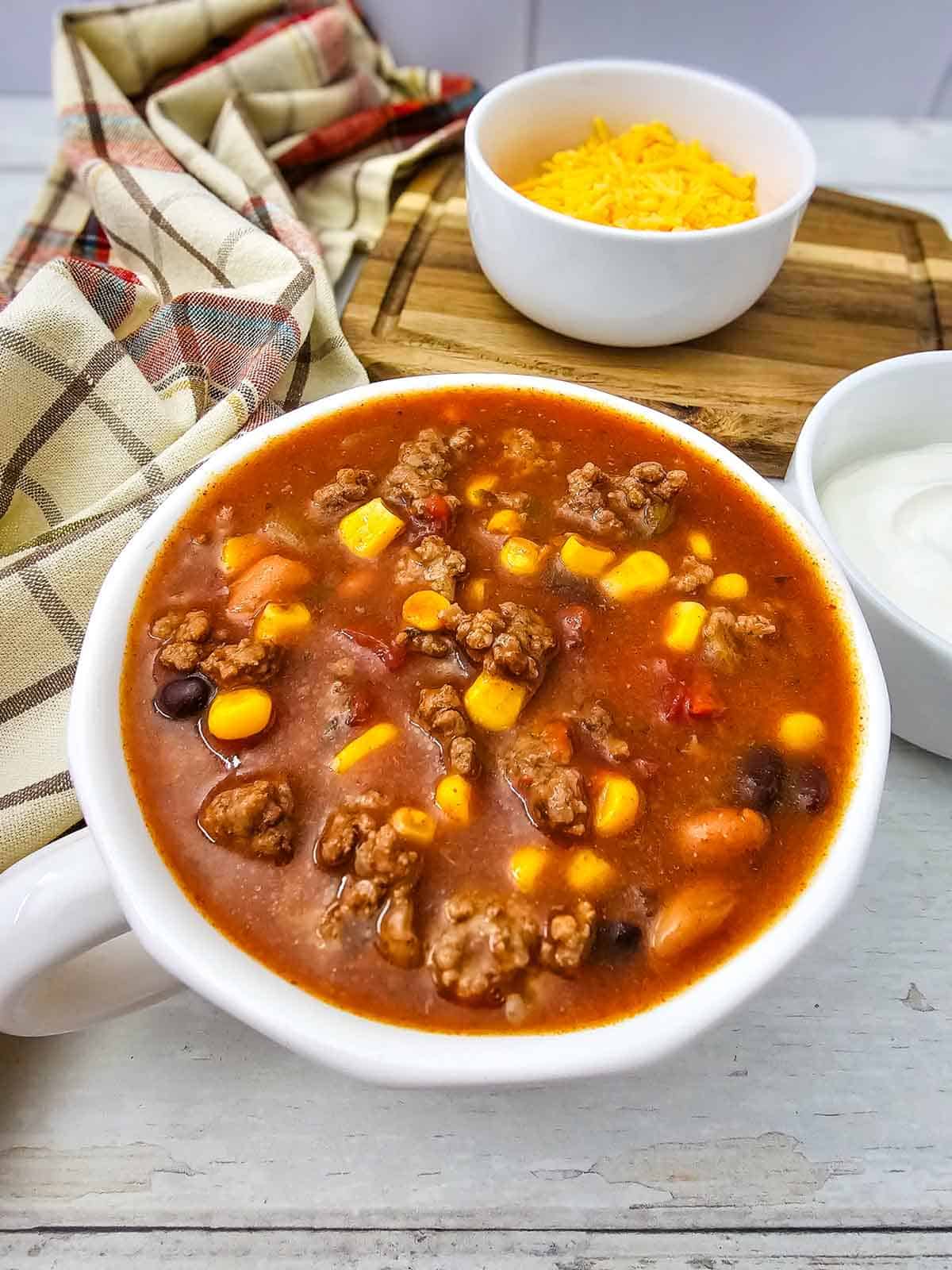 This easy 7 Can Taco Soup is the ultimate cozy dinner when you want big flavor with minimal prep! Loaded with seasoned ground beef, black beans, pinto beans, corn, diced tomatoes, green chilis and enchilada sauce, this hearty Taco Soup Recipe comes together with simple pantry staples in one pot. Taco seasoning, ranch seasoning, garlic, smoked paprika and cumin give every spoonful bold Tex-Mex flavor. Add this easy soup to your list of One Pot Dinner Ideas, Ground Beef Soup Recipes, Easy Taco Soup Recipes and Comfort Food Recipes. It’s perfect for busy weeknights, chilly fall dinners, meal prep or feeding the whole family. If you love Mexican Inspired Recipes, hearty Beef Soup Recipes and easy canned food recipes, save this 7 Can Taco Soup Recipe for a warm and satisfying dinner everyone will love!