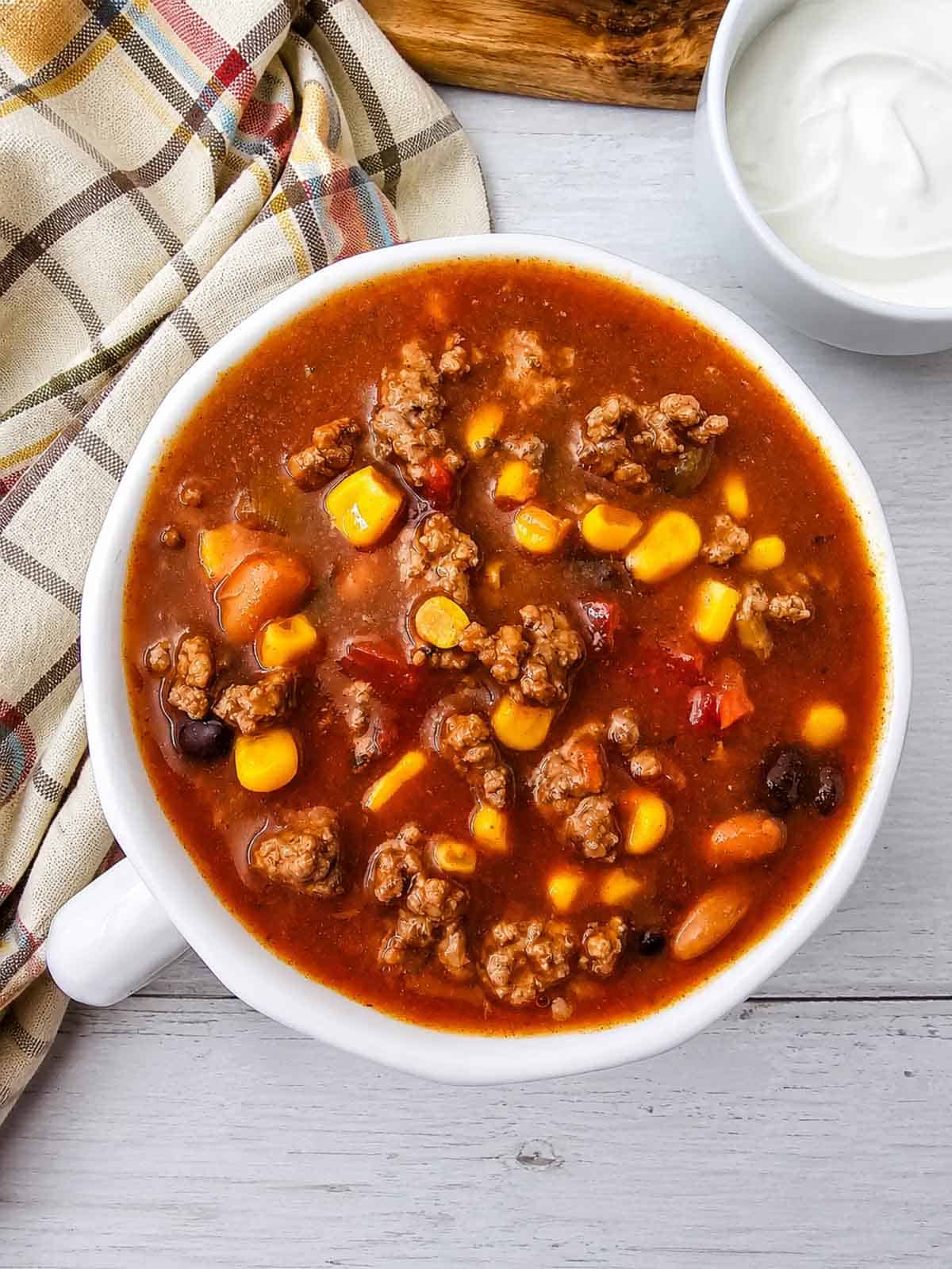 This easy 7 Can Taco Soup is the ultimate cozy dinner when you want big flavor with minimal prep! Loaded with seasoned ground beef, black beans, pinto beans, corn, diced tomatoes, green chilis and enchilada sauce, this hearty Taco Soup Recipe comes together with simple pantry staples in one pot. Taco seasoning, ranch seasoning, garlic, smoked paprika and cumin give every spoonful bold Tex-Mex flavor. Add this easy soup to your list of One Pot Dinner Ideas, Ground Beef Soup Recipes, Easy Taco Soup Recipes and Comfort Food Recipes. It’s perfect for busy weeknights, chilly fall dinners, meal prep or feeding the whole family. If you love Mexican Inspired Recipes, hearty Beef Soup Recipes and easy canned food recipes, save this 7 Can Taco Soup Recipe for a warm and satisfying dinner everyone will love!
