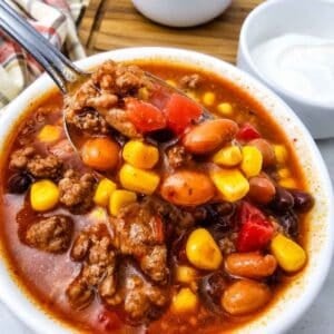 This easy 7 Can Taco Soup is the ultimate cozy dinner when you want big flavor with minimal prep! Loaded with seasoned ground beef, black beans, pinto beans, corn, diced tomatoes, green chilis and enchilada sauce, this hearty Taco Soup Recipe comes together with simple pantry staples in one pot. Taco seasoning, ranch seasoning, garlic, smoked paprika and cumin give every spoonful bold Tex-Mex flavor. Add this easy soup to your list of One Pot Dinner Ideas, Ground Beef Soup Recipes, Easy Taco Soup Recipes and Comfort Food Recipes. It’s perfect for busy weeknights, chilly fall dinners, meal prep or feeding the whole family. If you love Mexican Inspired Recipes, hearty Beef Soup Recipes and easy canned food recipes, save this 7 Can Taco Soup Recipe for a warm and satisfying dinner everyone will love!