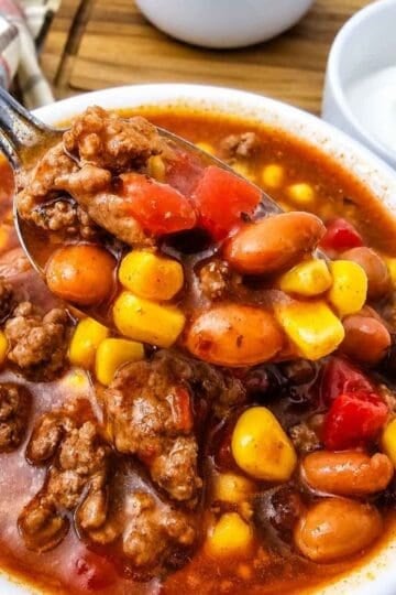 This easy 7 Can Taco Soup is the ultimate cozy dinner when you want big flavor with minimal prep! Loaded with seasoned ground beef, black beans, pinto beans, corn, diced tomatoes, green chilis and enchilada sauce, this hearty Taco Soup Recipe comes together with simple pantry staples in one pot. Taco seasoning, ranch seasoning, garlic, smoked paprika and cumin give every spoonful bold Tex-Mex flavor. Add this easy soup to your list of One Pot Dinner Ideas, Ground Beef Soup Recipes, Easy Taco Soup Recipes and Comfort Food Recipes. It’s perfect for busy weeknights, chilly fall dinners, meal prep or feeding the whole family. If you love Mexican Inspired Recipes, hearty Beef Soup Recipes and easy canned food recipes, save this 7 Can Taco Soup Recipe for a warm and satisfying dinner everyone will love!