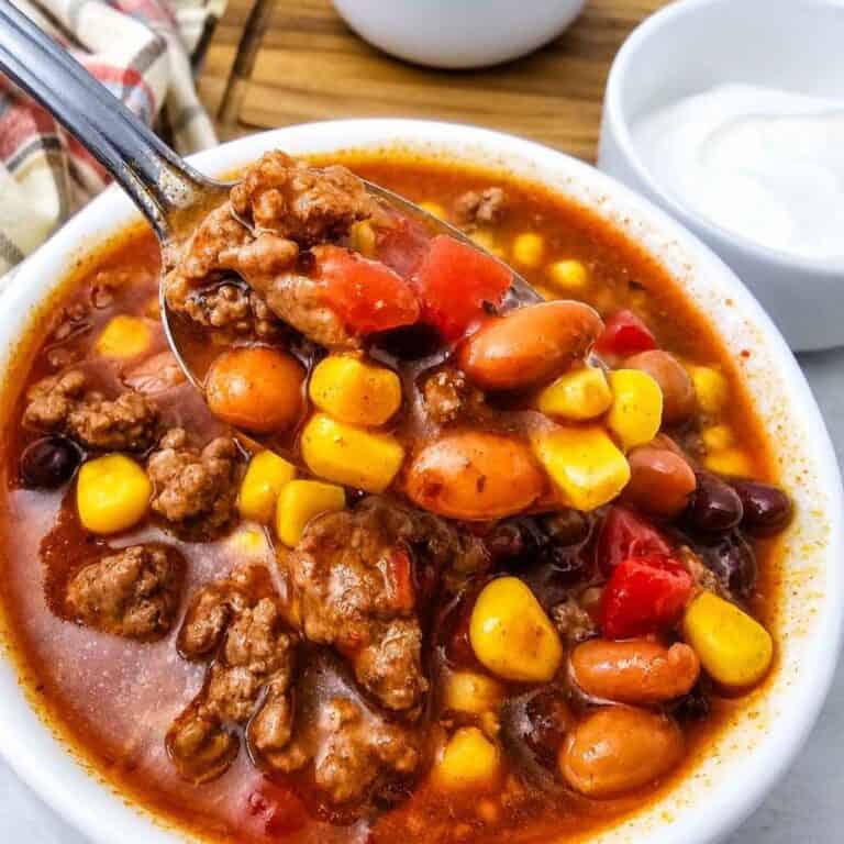 This easy 7 Can Taco Soup is the ultimate cozy dinner when you want big flavor with minimal prep! Loaded with seasoned ground beef, black beans, pinto beans, corn, diced tomatoes, green chilis and enchilada sauce, this hearty Taco Soup Recipe comes together with simple pantry staples in one pot. Taco seasoning, ranch seasoning, garlic, smoked paprika and cumin give every spoonful bold Tex-Mex flavor. Add this easy soup to your list of One Pot Dinner Ideas, Ground Beef Soup Recipes, Easy Taco Soup Recipes and Comfort Food Recipes. It’s perfect for busy weeknights, chilly fall dinners, meal prep or feeding the whole family. If you love Mexican Inspired Recipes, hearty Beef Soup Recipes and easy canned food recipes, save this 7 Can Taco Soup Recipe for a warm and satisfying dinner everyone will love!