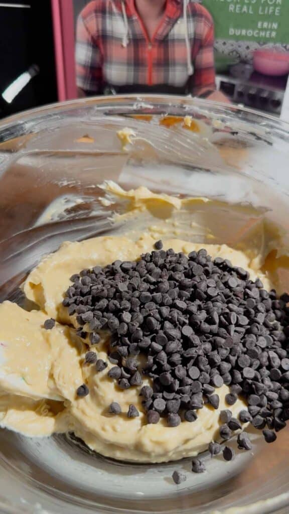 mini chocolate chips on top of butter and cream cheese mixture in a glass mixing bowl