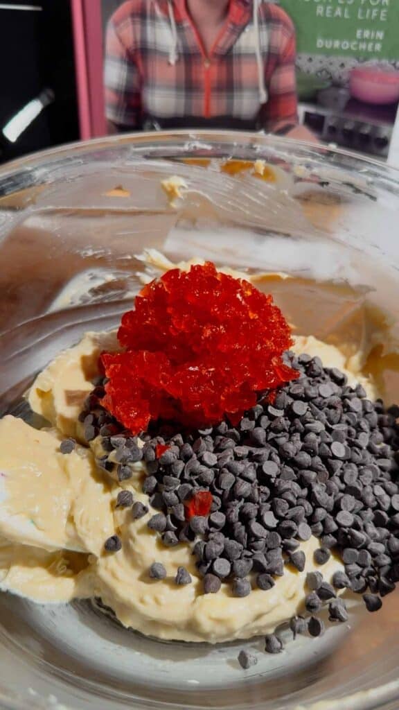 chopped cherries and mini chocolate chips on top of butter and cream cheese mixture in a glass bowl