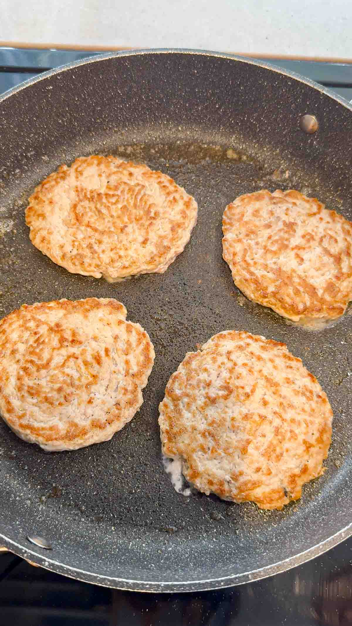 cooked chicken burger patties in a skillet