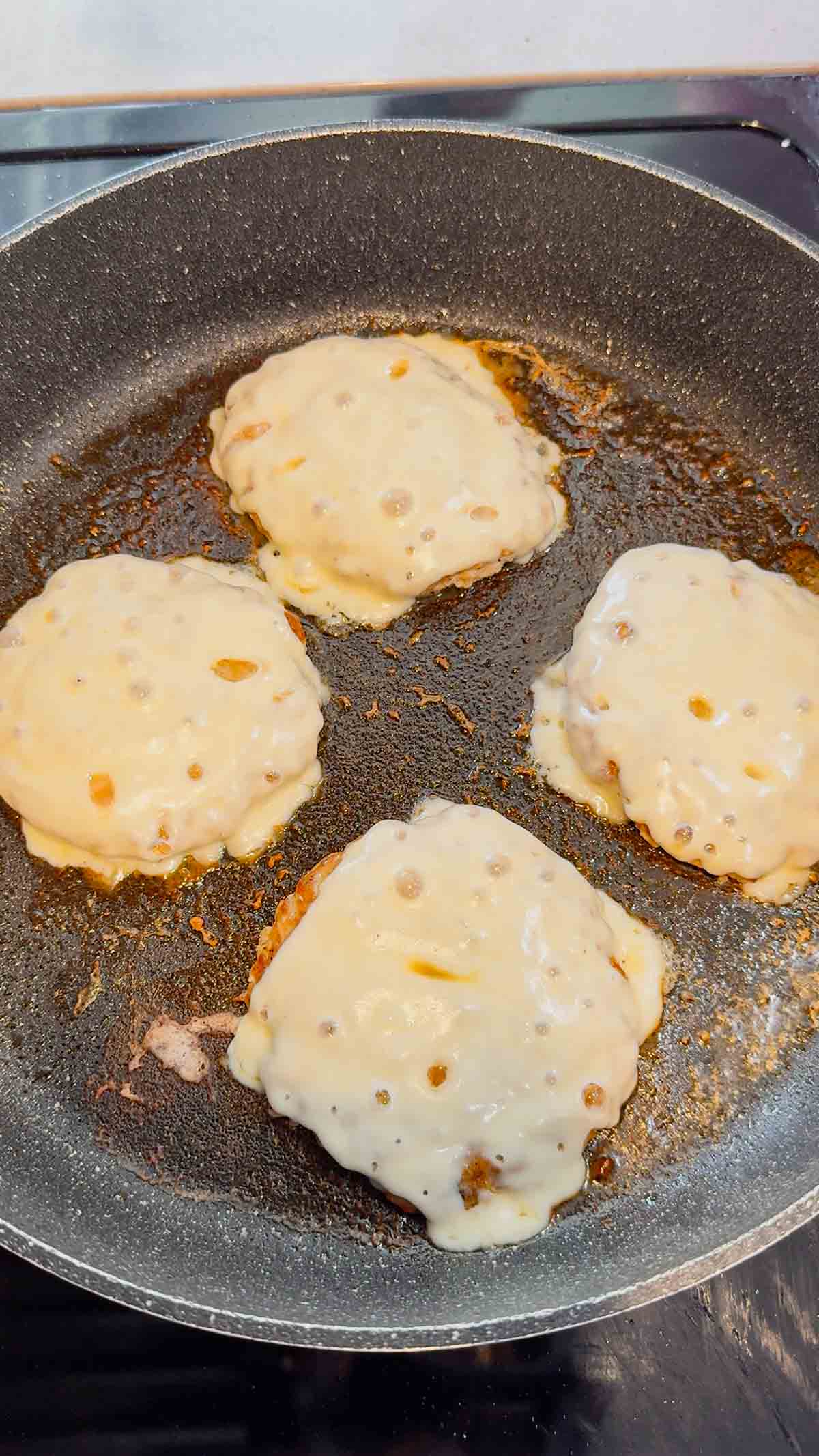 melted cheese on top of chicken patties in a skillet