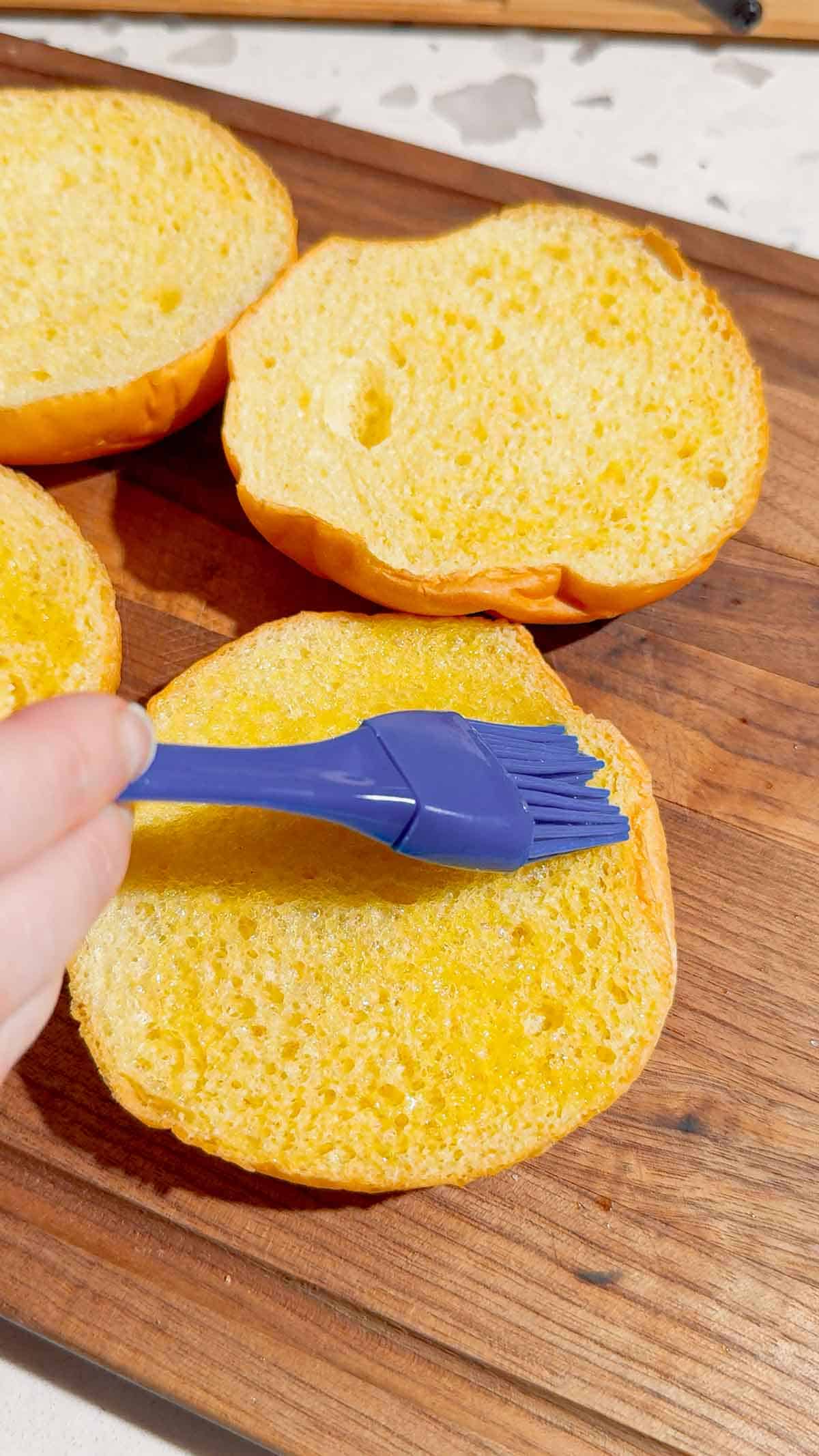 brushing melted butter on brioche buns