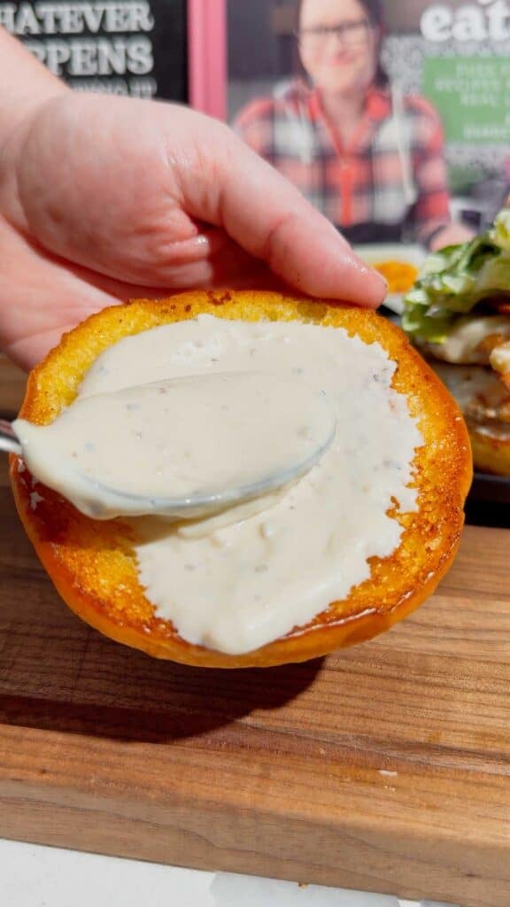 spreading ceasar dressing on a toasted bun