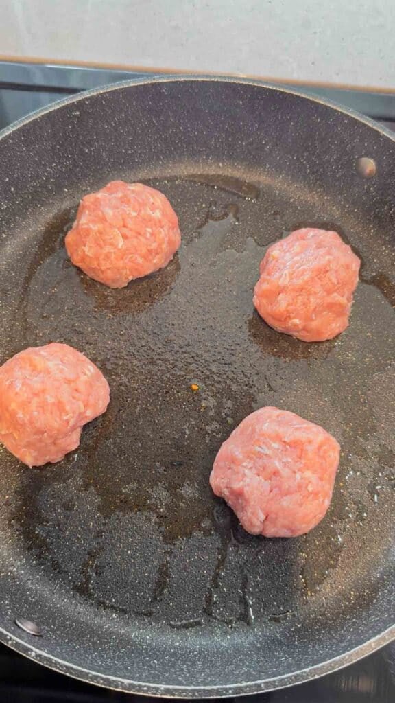 balls of ground chicken in a skillet