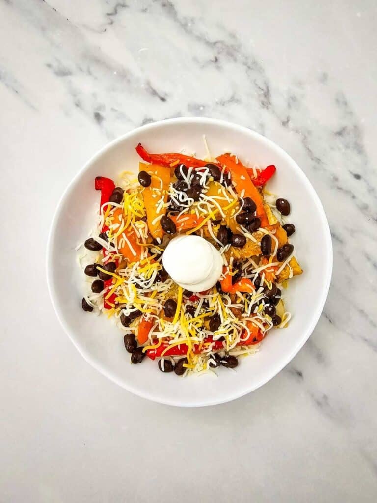 These easy Chicken Fajita Bowls are a flavorful weeknight dinner loaded with juicy seasoned chicken, colorful bell peppers, onions, fluffy rice, black beans, shredded cheese, and sour cream. If you love Chicken Fajita Bowl Recipes, Sheet Pan Chicken Fajitas, Mexican Chicken Bowls, or easy Chicken and Rice Bowls, this simple dinner is a must-try! The chicken and vegetables roast together on one sheet pan for easy prep and cleanup, then everything is piled into a delicious fajita rice bowl. Perfect for busy families, meal prep, quick dinners, and customizable meals everyone can top their own way. Save this Chicken Fajita Rice Bowl recipe when you need Easy Chicken Dinner Ideas, Mexican Dinner Recipes, Healthy Fajita Bowls, Sheet Pan Dinners, or quick family meals packed with bold fajita flavor!