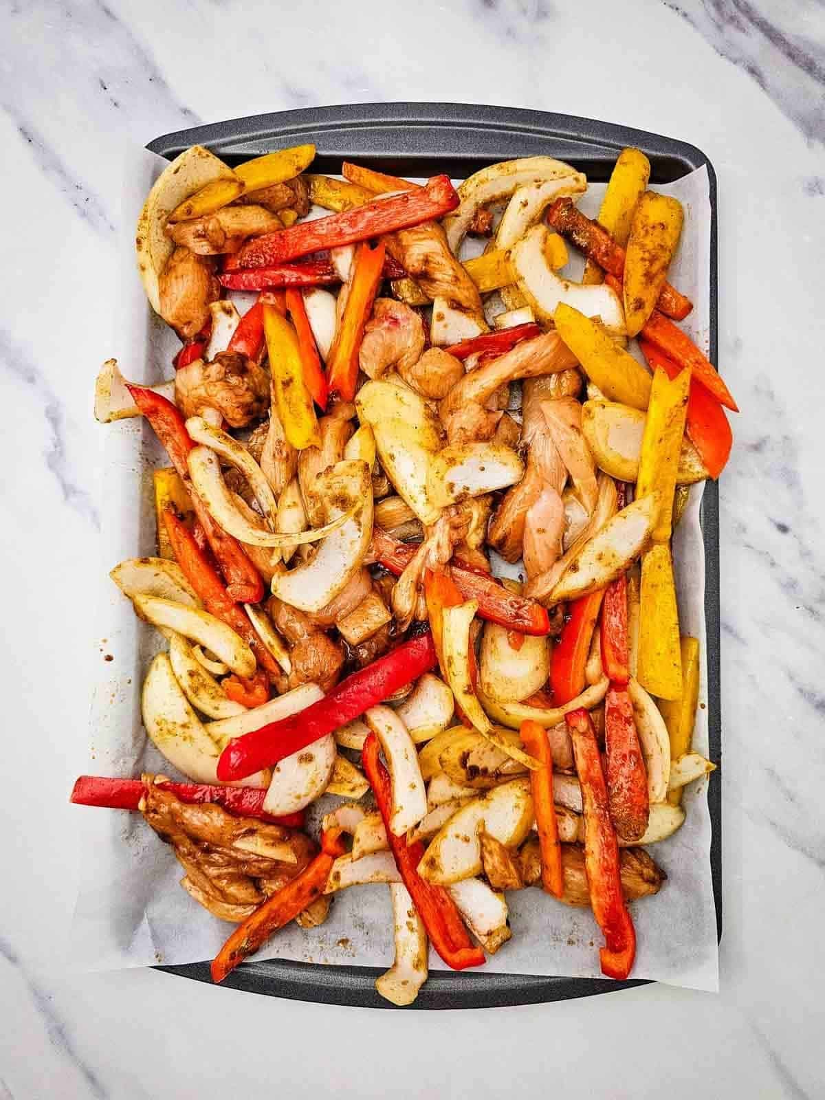 chicken fajitas mixture on a baking sheet before cooking