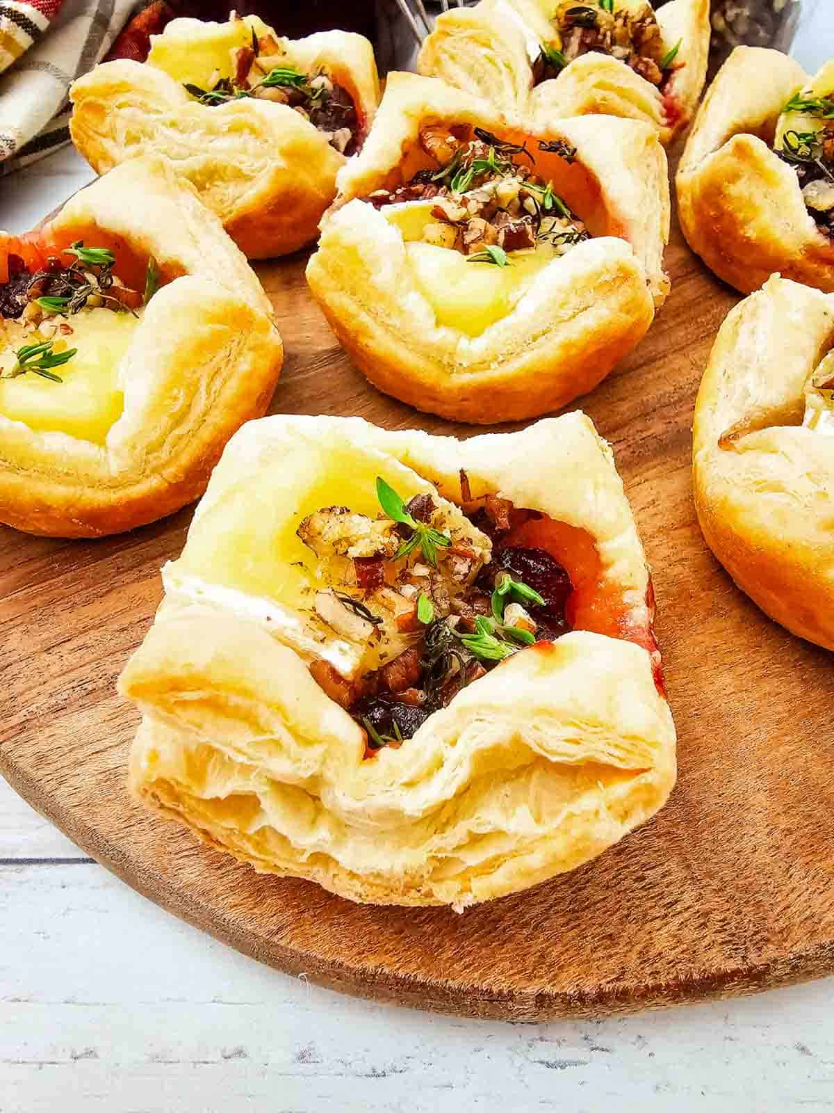 These Puff Pastry Cranberry Brie Bites are an easy holiday appetizer for entertaining. Flaky puff pastry is filled with creamy Brie cheese, sweet-tart cranberry sauce, crunchy pecans, and fresh thyme, then baked until golden and perfectly melty. This Cranberry Brie Bites recipe is perfect for Christmas appetizers, Thanksgiving appetizers, holiday party food, New Year's Eve appetizers, and easy finger foods for entertaining. If you love baked Brie, puff pastry appetizers, cranberry appetizers and Brie recipes, these bite-sized treats are a must-try. With just 5 ingredients and 15 minutes of prep, these easy holiday appetizers look elegant without the extra work. Save these Cranberry Brie Puff Pastry Bites for your next holiday gathering, potluck, Christmas dinner, or party!