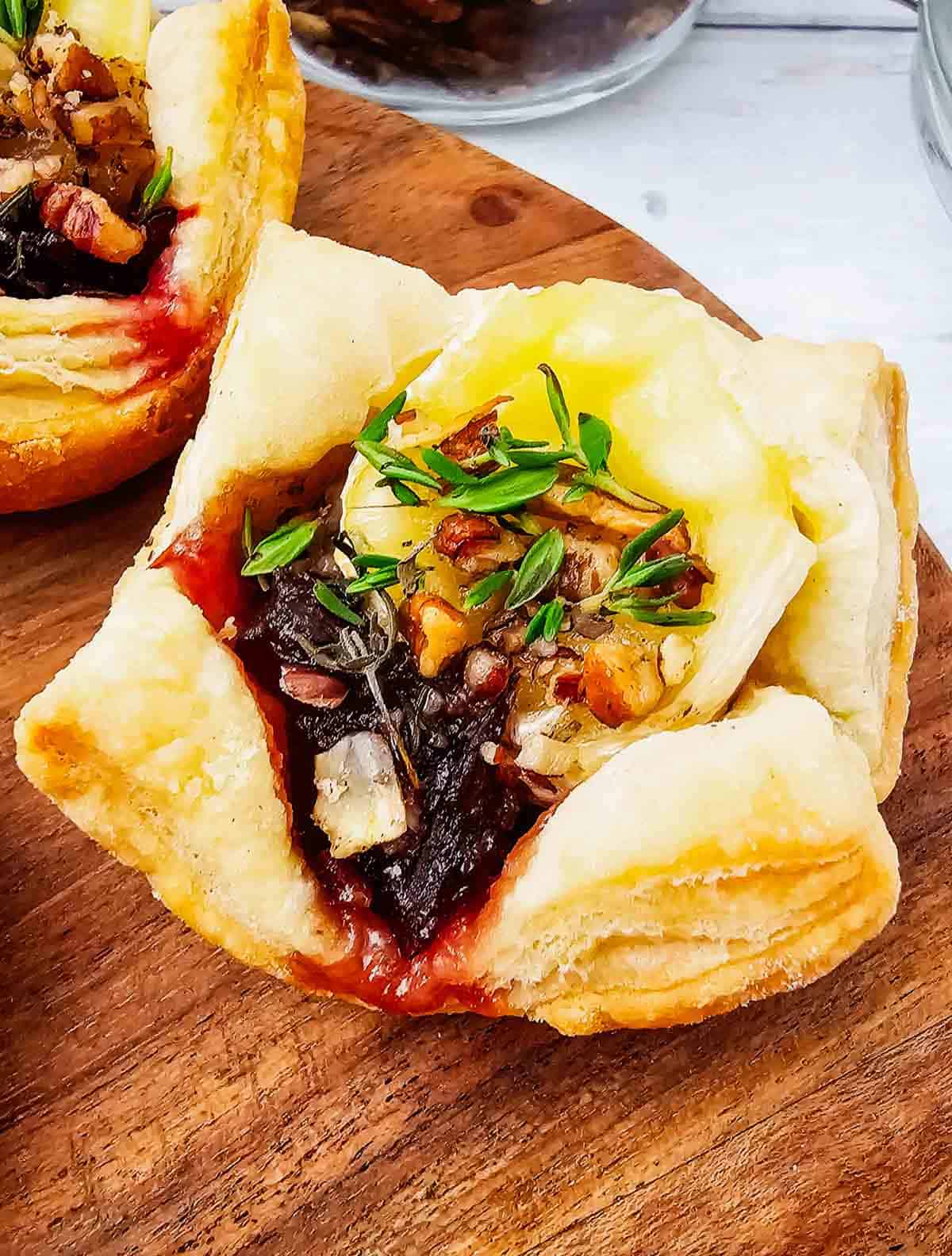 These Puff Pastry Cranberry Brie Bites are an easy holiday appetizer for entertaining. Flaky puff pastry is filled with creamy Brie cheese, sweet-tart cranberry sauce, crunchy pecans, and fresh thyme, then baked until golden and perfectly melty. This Cranberry Brie Bites recipe is perfect for Christmas appetizers, Thanksgiving appetizers, holiday party food, New Year's Eve appetizers, and easy finger foods for entertaining. If you love baked Brie, puff pastry appetizers, cranberry appetizers and Brie recipes, these bite-sized treats are a must-try. With just 5 ingredients and 15 minutes of prep, these easy holiday appetizers look elegant without the extra work. Save these Cranberry Brie Puff Pastry Bites for your next holiday gathering, potluck, Christmas dinner, or party!