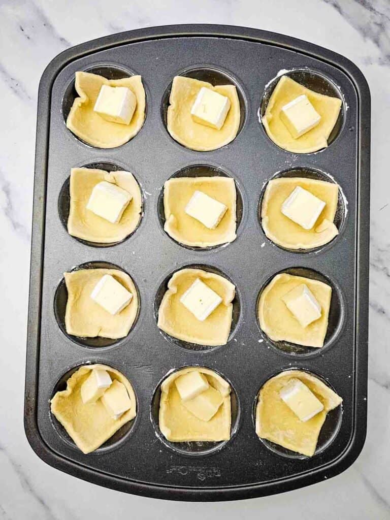 cubes of brie cheese in puff pastry lined muffin tins