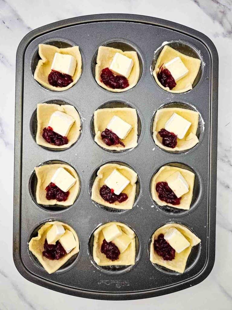 puff pastry in muffin tins filled with brie and cranberry sauce